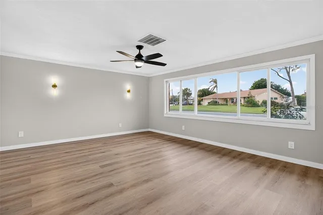 a view of an empty room with a window and wooden floor