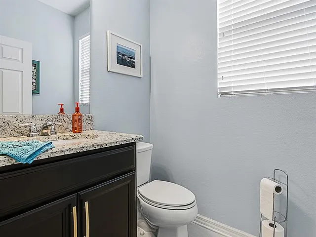 a bathroom with a granite countertop sink a large mirror a toilet and a shower