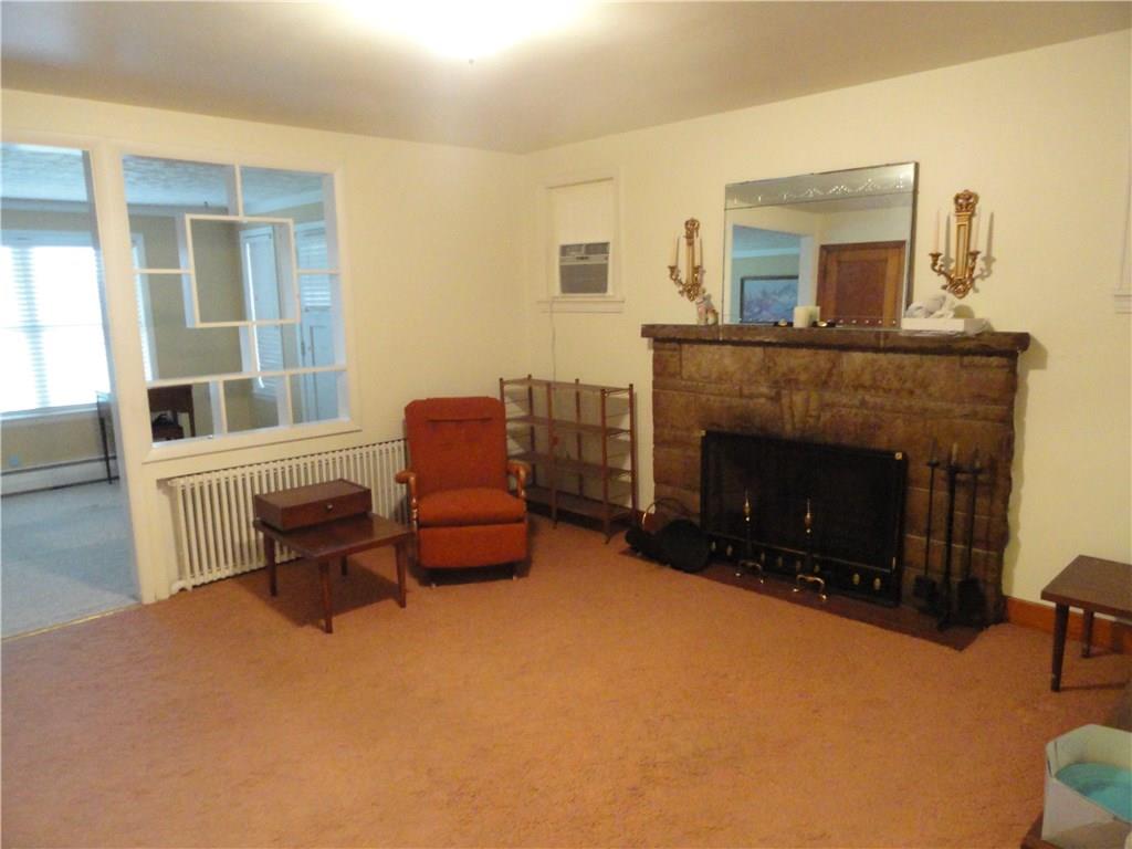 Beautiful stone wood burning fireplace in living room. Open view to family room