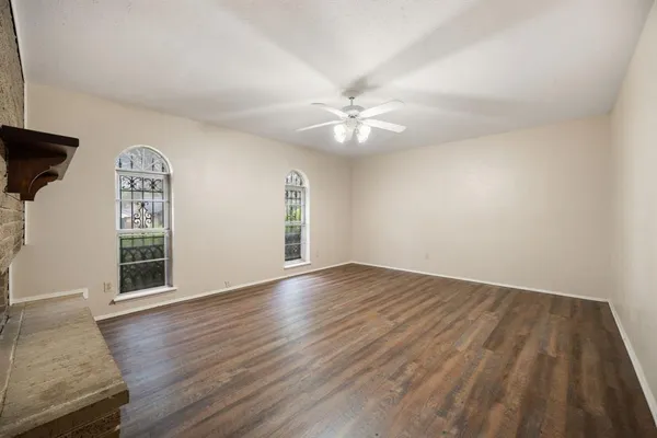 an empty room with wooden floor fireplace and windows