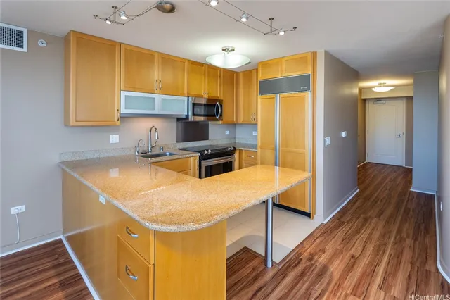 a kitchen with stainless steel appliances a stove a refrigerator a sink and dishwasher with wooden floor