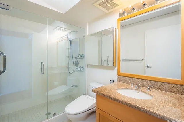 a bathroom with a granite countertop sink toilet mirror and shower
