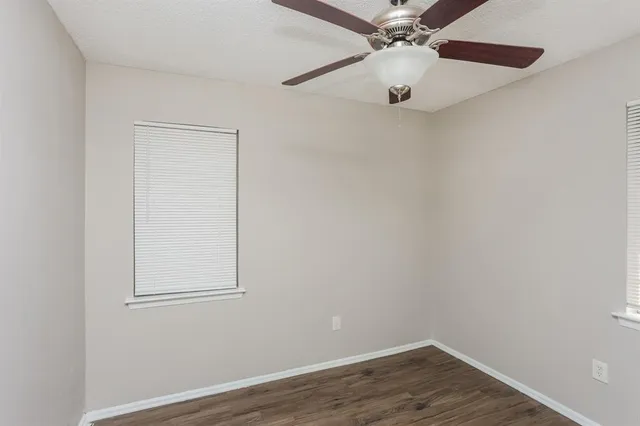 an empty room with a chandelier fan and wooden floor