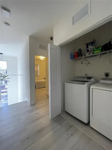 a view of storage and utility room with closet and wooden floor