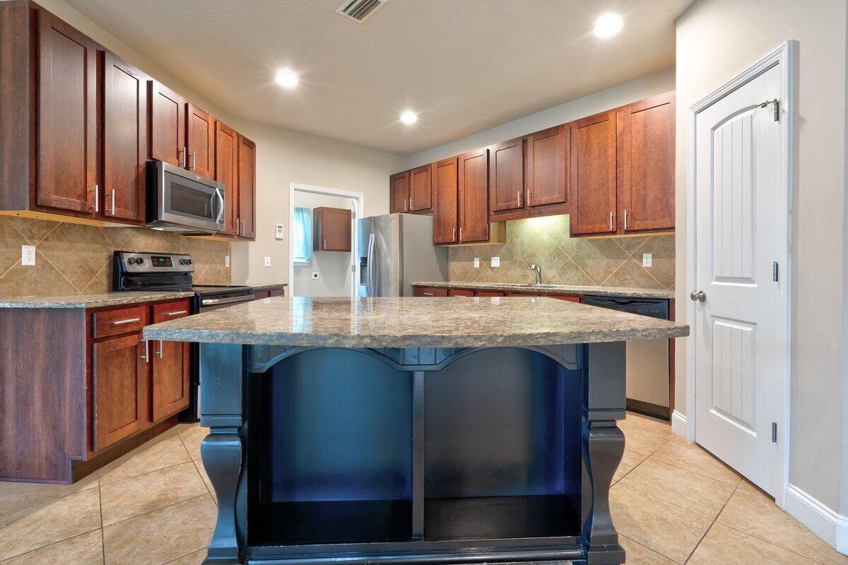 4614 Hermosa Road Crestview, FL 32539 - Photo 5 of 23 a kitchen with stainless steel appliances granite countertop wooden cabinets a stove top oven a sink and dishwasher