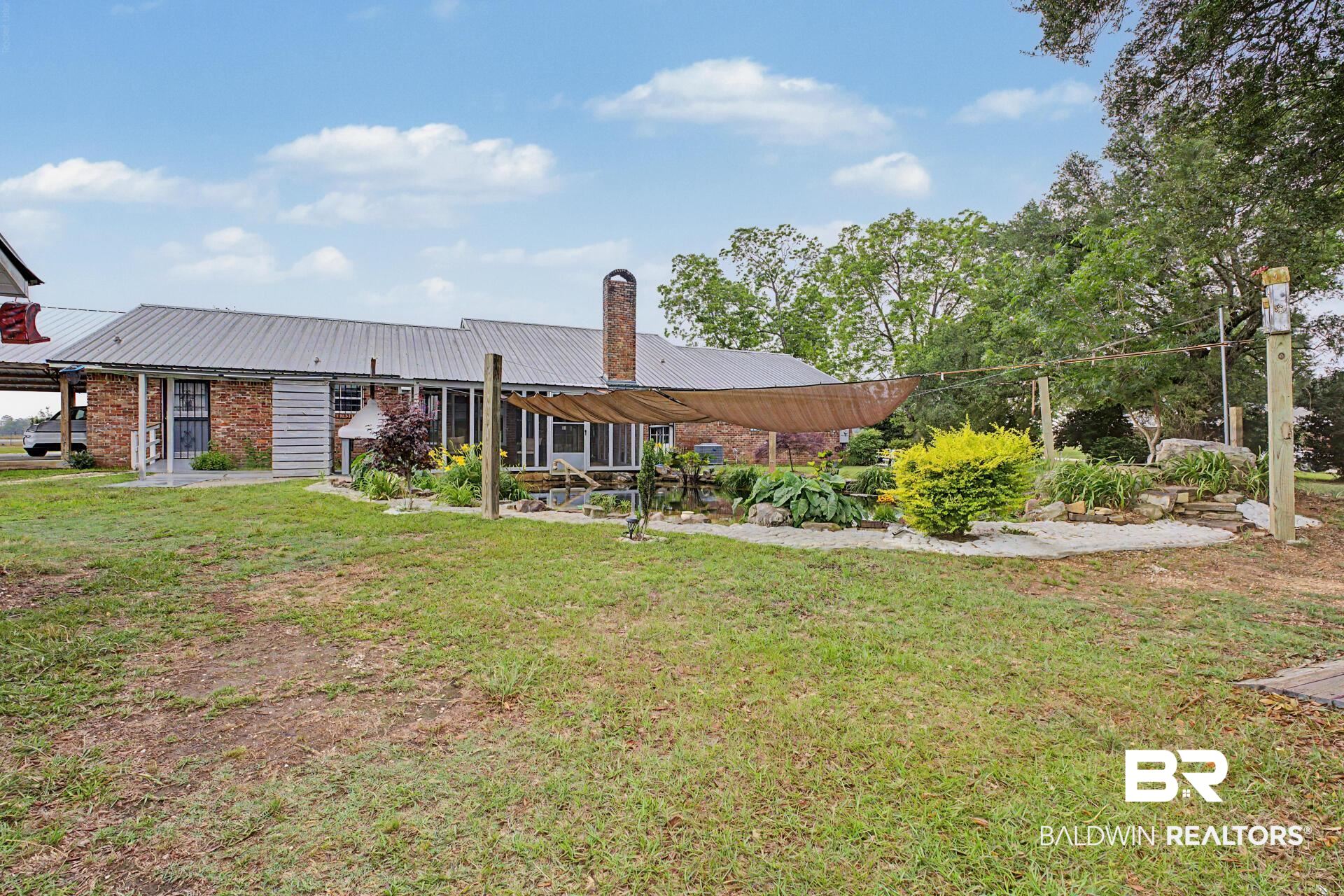3791 Robinsonville Road Atmore, AL 36502 - Photo 16 of 47 Rear exterior featuring a brick facade and metal roof