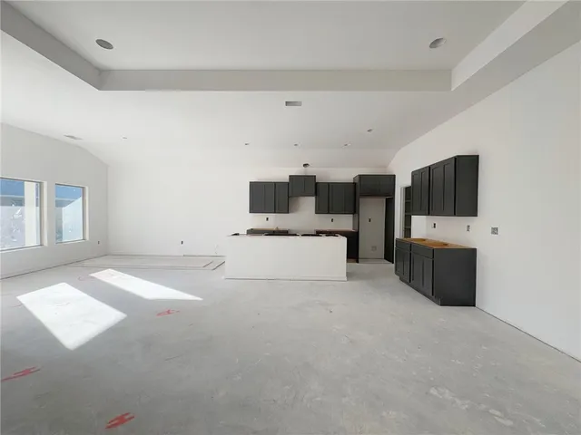 a room with kitchen island a white cabinets and a refrigerator