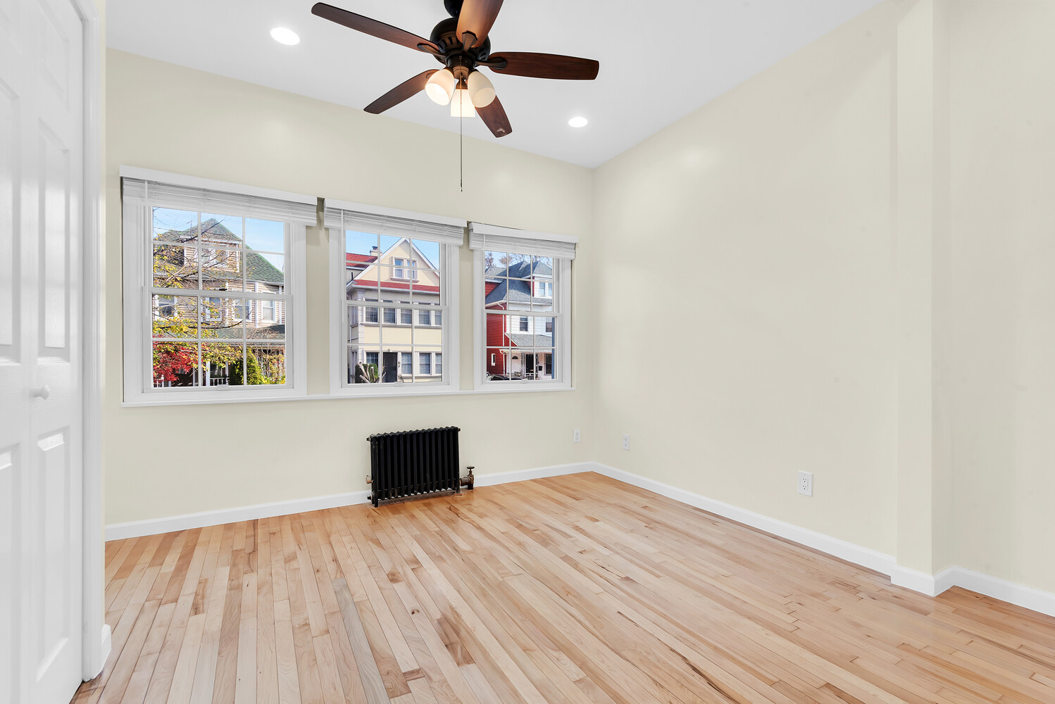a view of empty room with wooden floor and fan