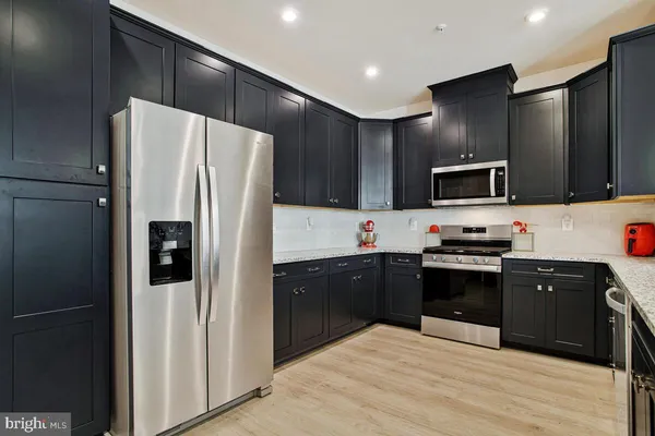 a kitchen with stainless steel appliances kitchen island granite countertop a refrigerator and a stove top oven