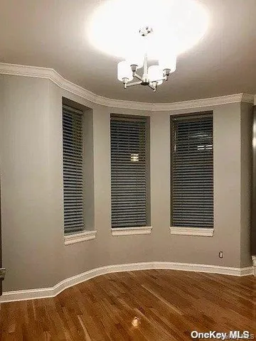 a view of an empty room with a window and chandelier