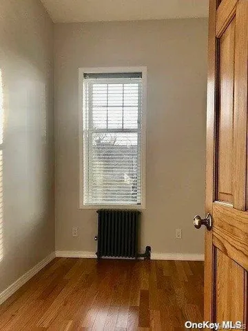an empty room with wooden floor and a window