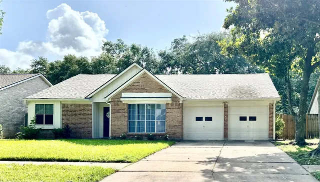 a view of a house with a yard and large tree