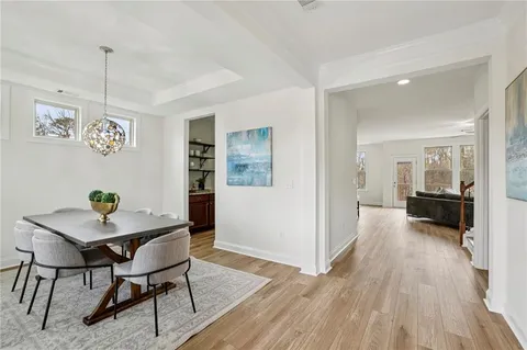 a view of a dining room and livingroom with furniture wooden floor a chandelier