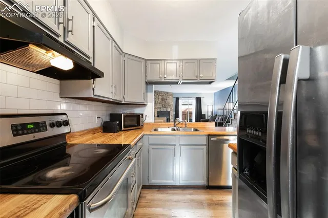 a kitchen with stainless steel appliances granite countertop a refrigerator a stove and a sink