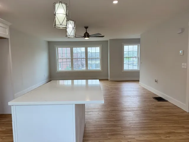 a view of an empty room with wooden floor and window