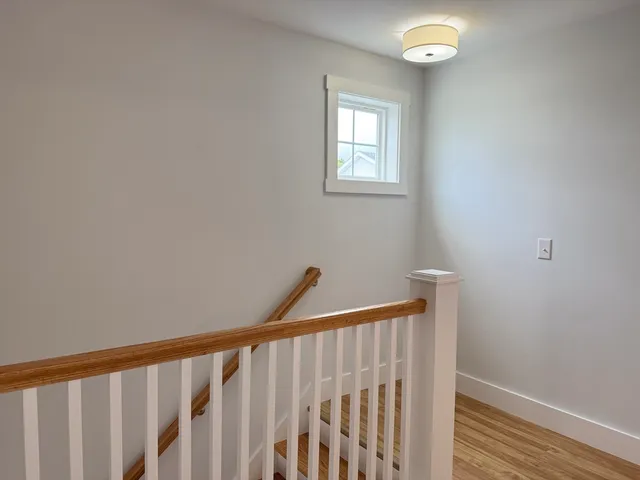 a view of a hallway with wooden floor and a window