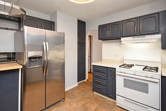 a kitchen with stainless steel appliances granite countertop a refrigerator and a stove top oven