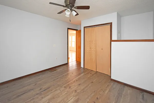 an empty room with wooden floor fan and windows