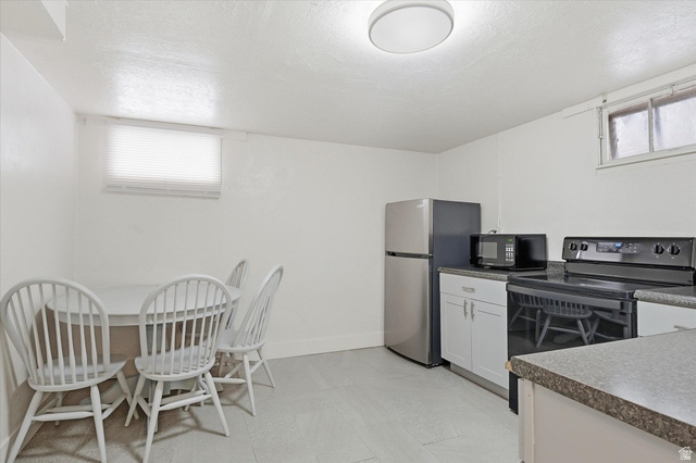 744 North 500 East Logan, UT 84321 - Photo 22 of 29 Basement Kitchen with black appliances, white cabinets, a textured ceiling, dark countertops, and light floors