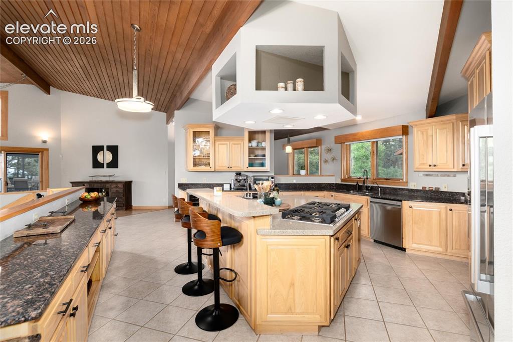 12730 Bridle Bit Road Colorado Springs, CO 80908 - Photo 6 of 50 Kitchen featuring a multi-level island with seating, a cooktop, and light wood cabinetry