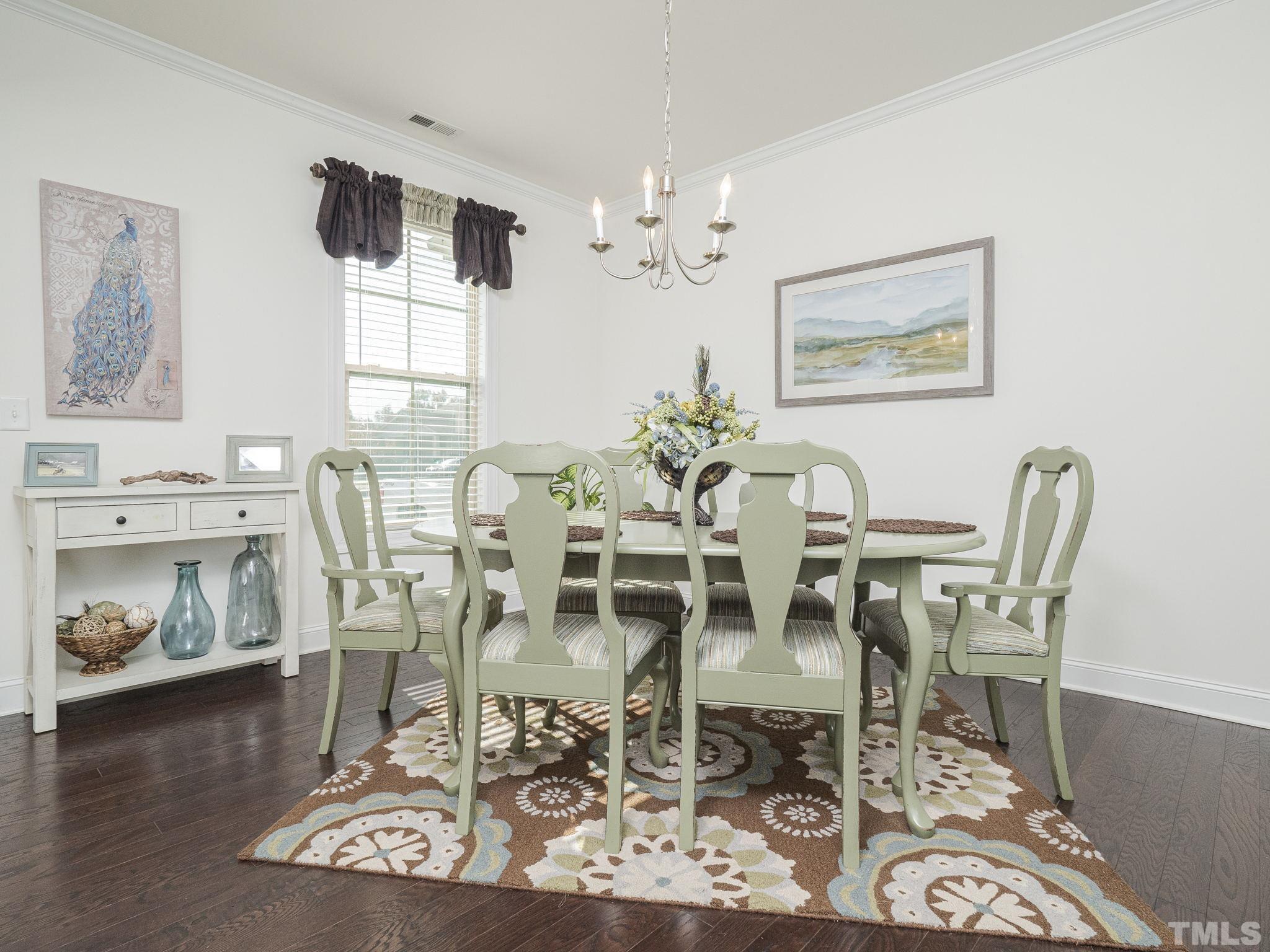 6812 Rising Sun Court Wake Forest, NC 27587 - Photo 3 of 29 a dining room with furniture a chandelier and wooden floor