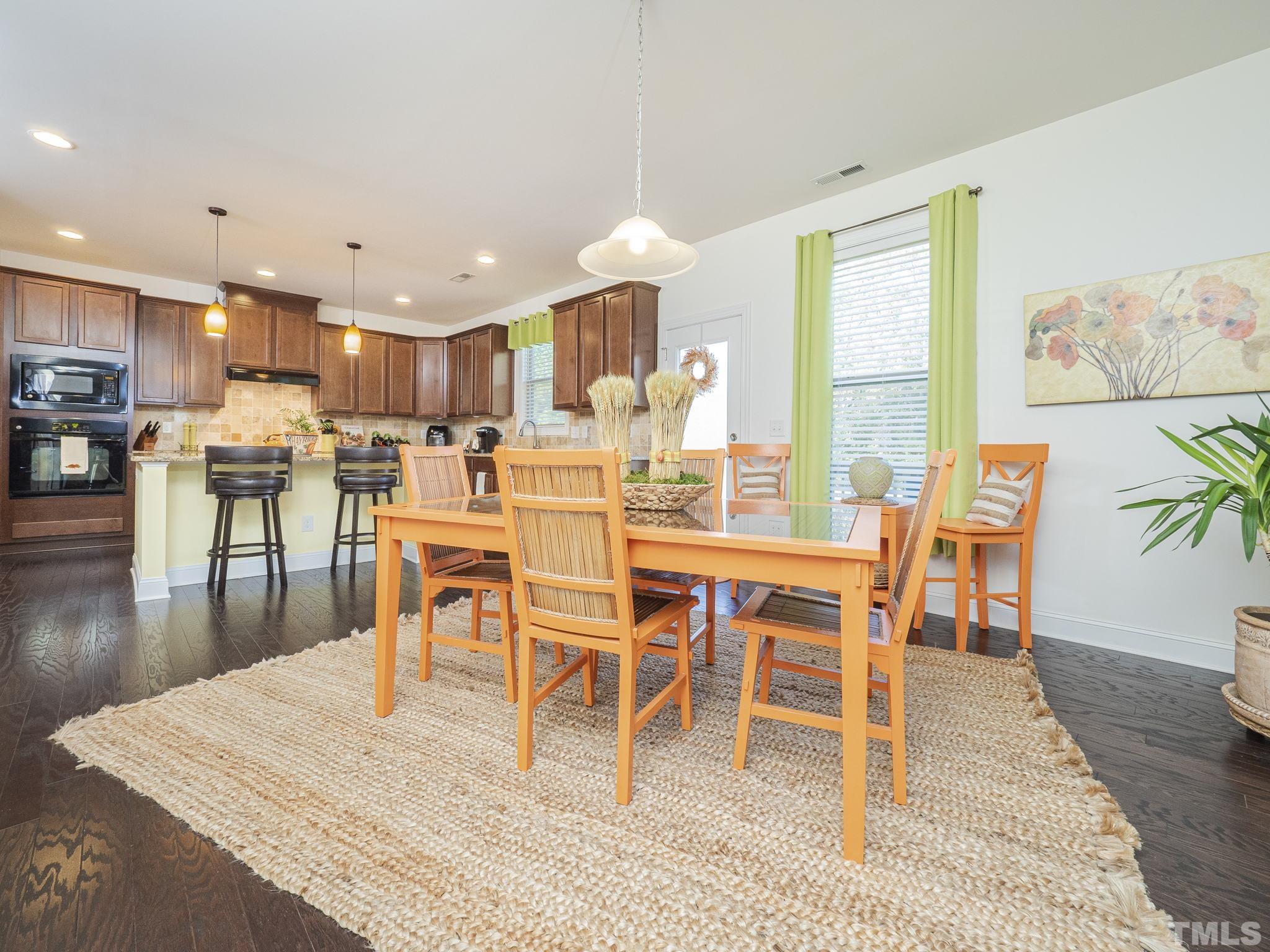 6812 Rising Sun Court Wake Forest, NC 27587 - Photo 8 of 29 a dining room with wooden floor a glass table and chairs