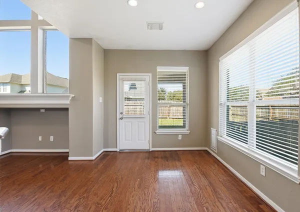 an empty room with wooden floor and windows