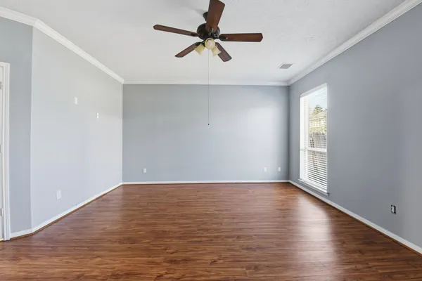 a view of an empty room with window and wooden floor