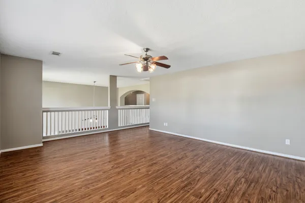 an empty room with wooden floor fan and windows