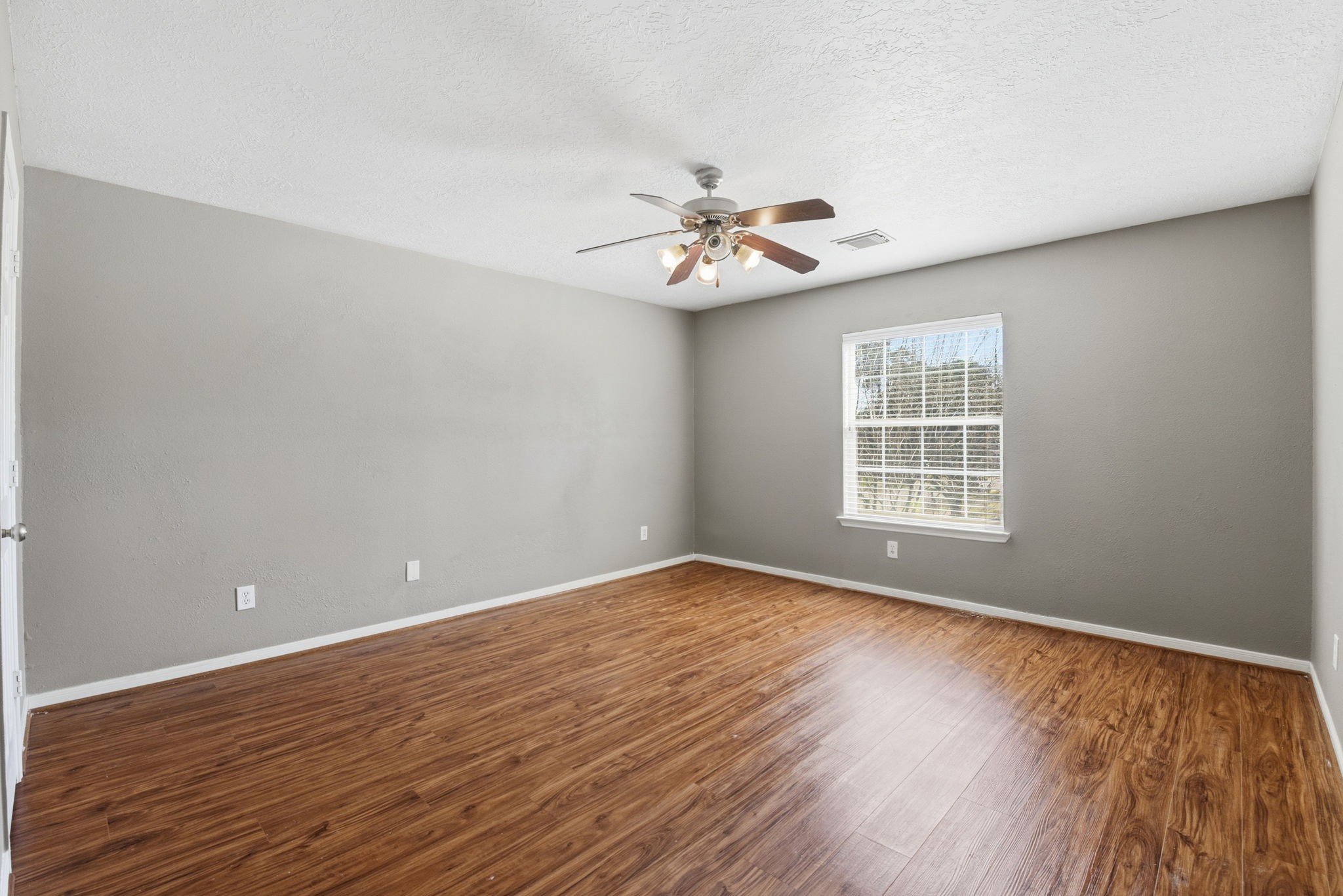 13902 Oneida Court Cypress, TX 77429 - Photo 45 of 48 an empty room with wooden floor chandelier fan and windows