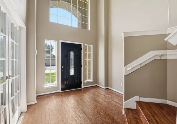 a view of an empty room with wooden floor and a window
