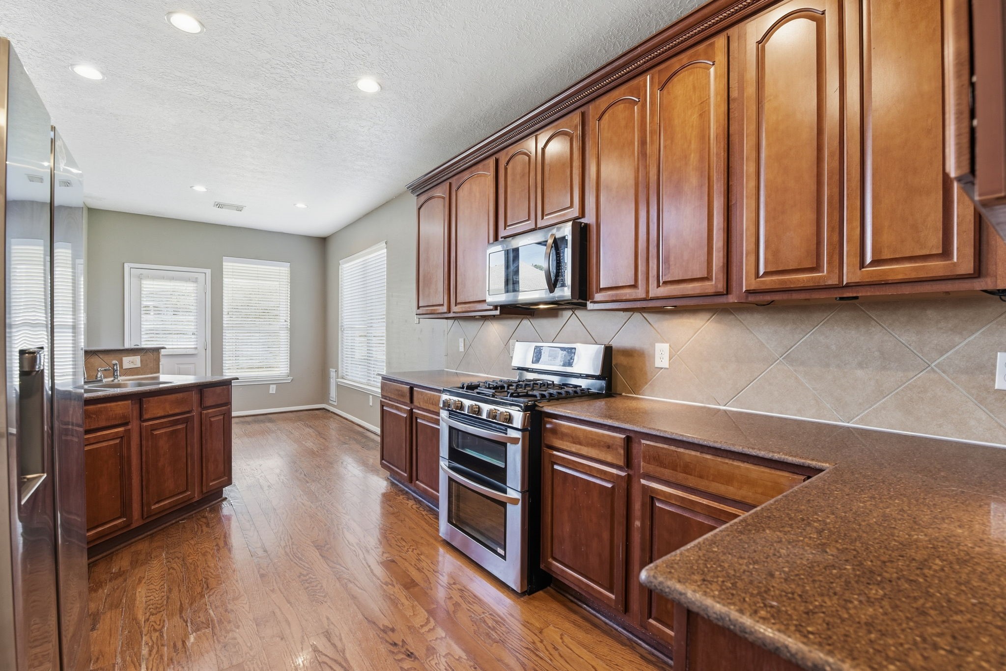 13902 Oneida Court Cypress, TX 77429 - Photo 10 of 48 a kitchen with stainless steel appliances granite countertop a stove a sink dishwasher and a microwave oven with wooden floor
