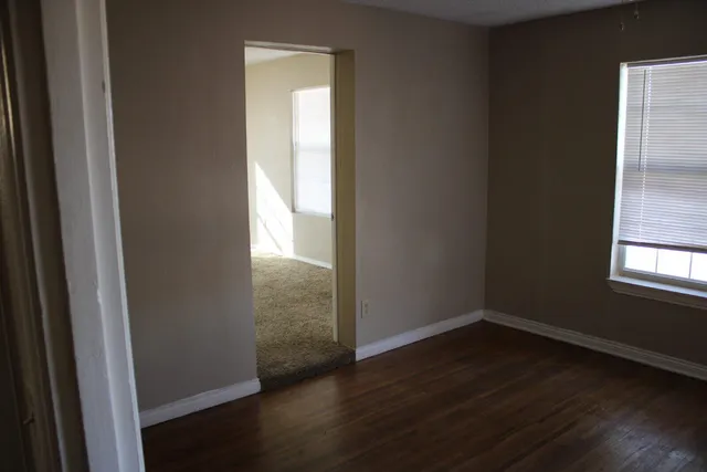 a view of an empty room with wooden floor and a window