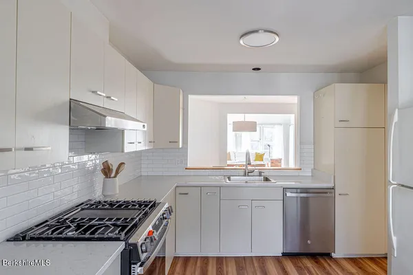 a kitchen with kitchen island white cabinets a sink a stove and wooden floors
