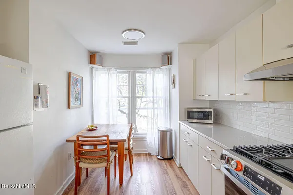 a kitchen with stainless steel appliances a stove a sink dishwasher and white cabinets with wooden floor