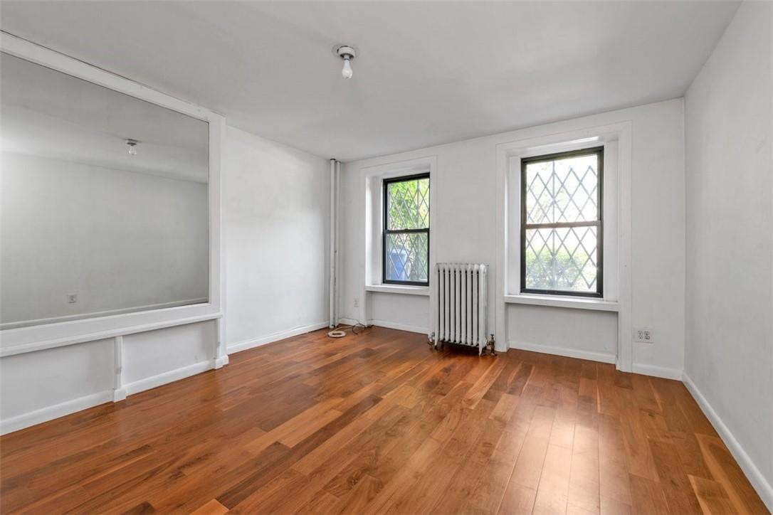 196 Decatur Street Brooklyn, NY 11233 - Photo 15 of 20 an empty room with wooden floor and windows