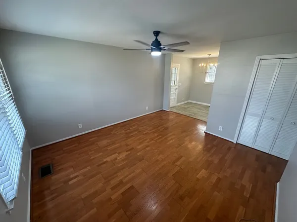an empty room with wooden floor and fan