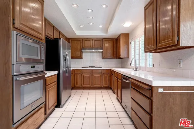 a kitchen with stainless steel appliances granite countertop a sink a stove top oven and cabinets