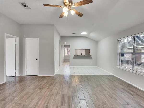 a view of empty room with wooden floor and fan