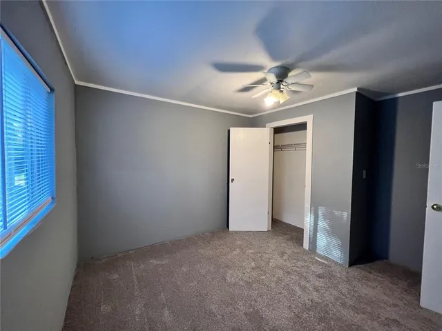 an empty room with a ceiling fan and a window