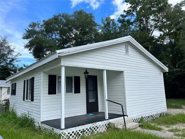 a view of house with a yard and potted plants