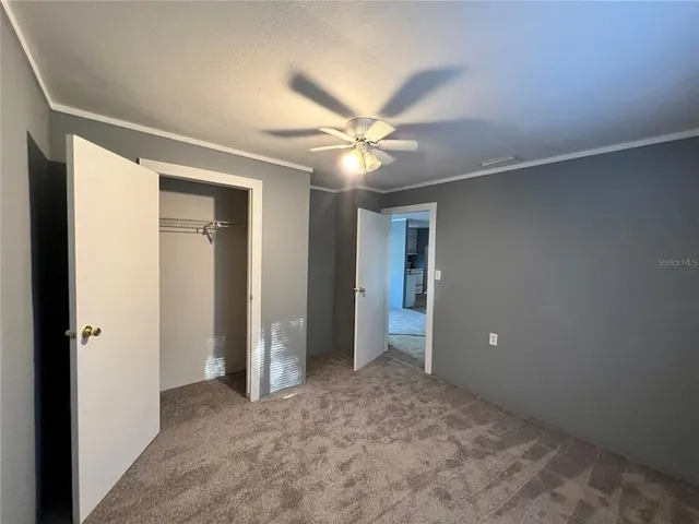 an empty room with closet and a ceiling fan