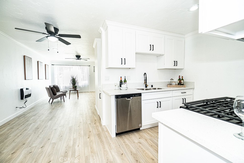 a kitchen with a white stove top oven and white cabinets with wooden floor