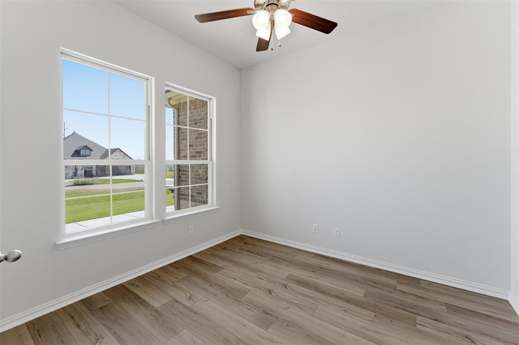 104 Snowy Owl Trail Rhome, TX 76078 - Photo 6 of 27 Room featuring a ceiling fan with light fixture, wood-finish flooring, and white baseboards