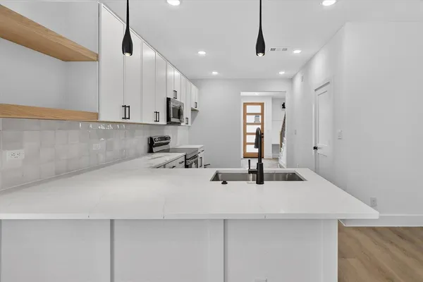 a kitchen with stainless steel appliances a sink a center island and cabinets