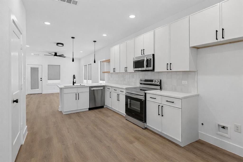 2835 Macon Street Dallas, TX 75215 - Photo 6 of 14 a kitchen with stainless steel appliances white cabinets a sink a stove a refrigerator and cabinets
