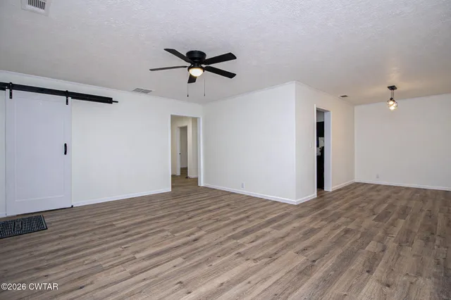 a view of empty room with wooden floor and ceiling fan