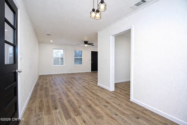 a view of an empty room with wooden floor and a window