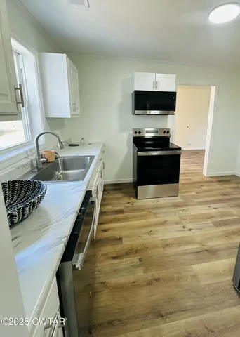 a kitchen with kitchen island a sink appliances and cabinets