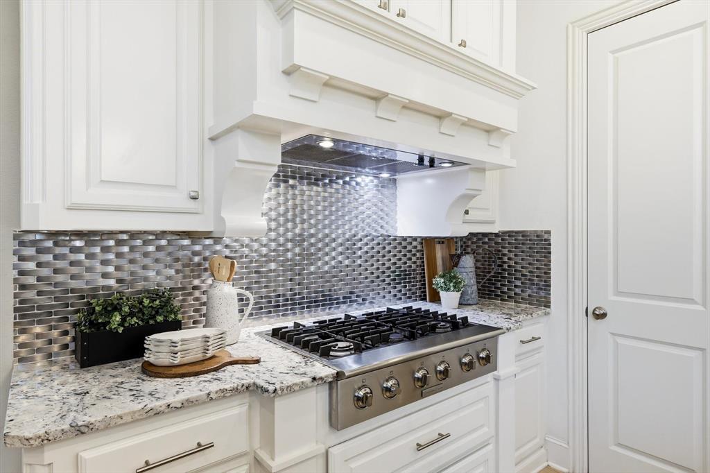 1933 Snapdragon Road Frisco, TX 75033 - Photo 12 of 40 Kitchen featuring a stainless steel gas range, custom white cabinetry, patterned tile backsplash, granite countertops, and a decorative range hood